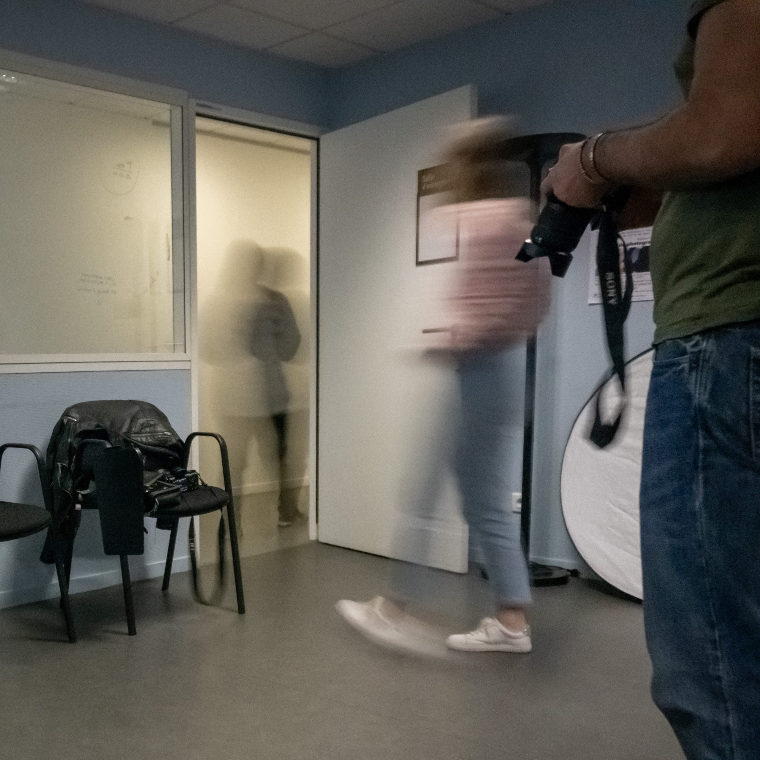 Deux personnes floues sorte d'une sale. Un homme tien un appareil photo au premier plan